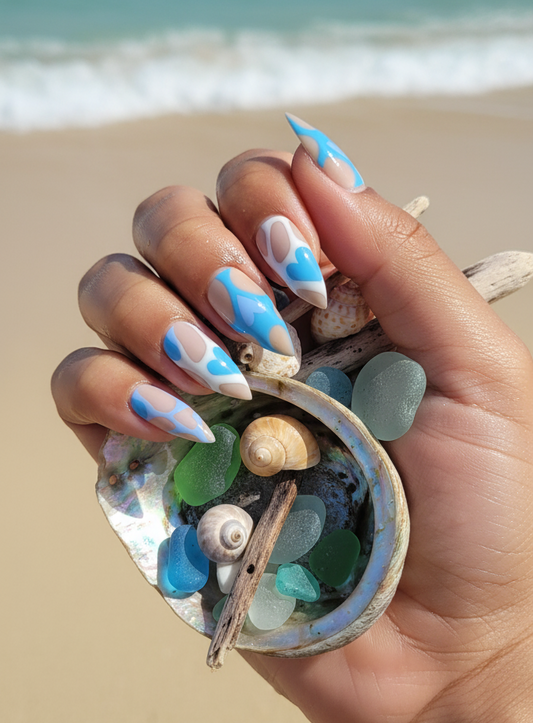 Hand holding a shell filled with seashells and beach treasures on a sandy beach.