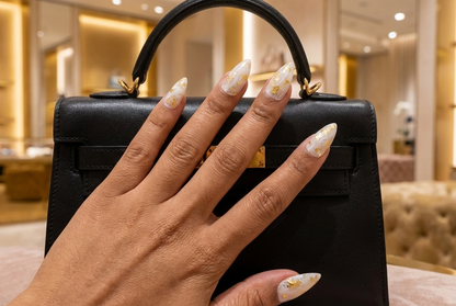 Black handbag held by a hand with manicured nails in a luxurious setting