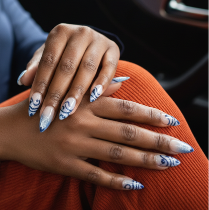 Person sitting in a car with hands on lap, wearing a dark blue outfit and red pants.